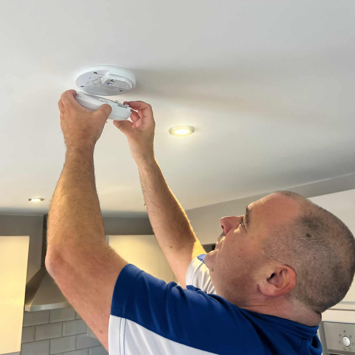 Smoke alarm installer fitting an alarm in a Bradley Stoke property